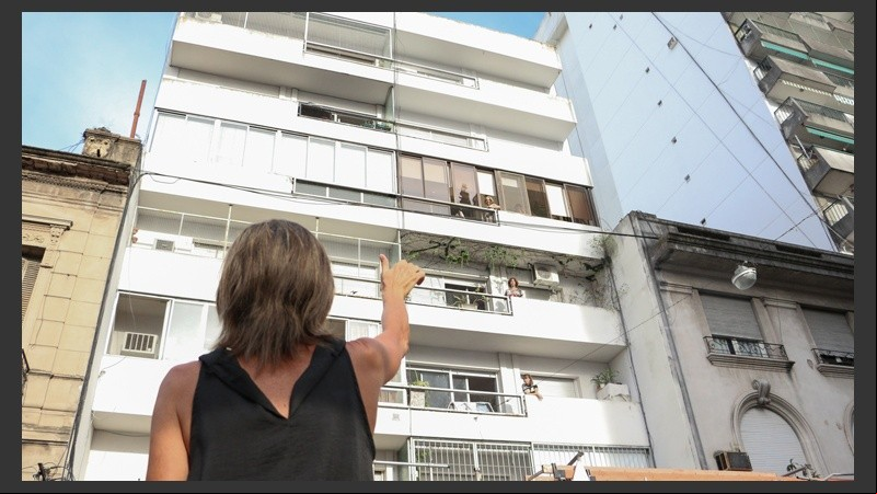 Una mujer se comunica con señas y gritos con su pariente en el edificio.