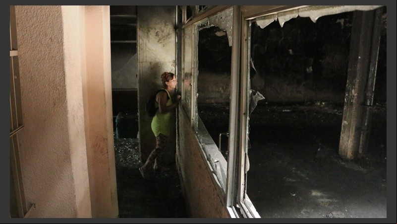 Una mujer mira el interior de la cochera incendiada.