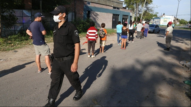 Un policía hace que se respete el distanciamiento en la fila. 