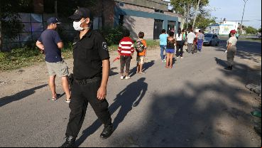 Un policía hace que se respete el distanciamiento en la fila.