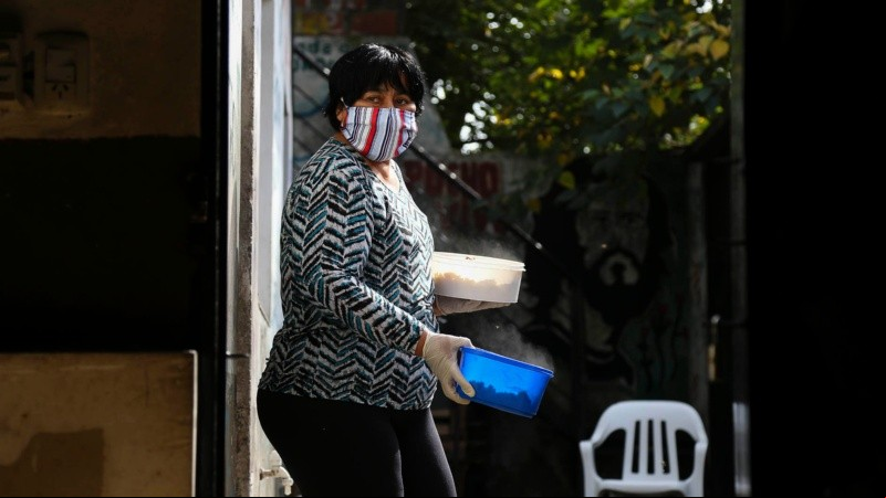 Mirta, una de las que participa activamente en el comedor, sale de la cocina con dos porciones de alimento listos para entregar. 