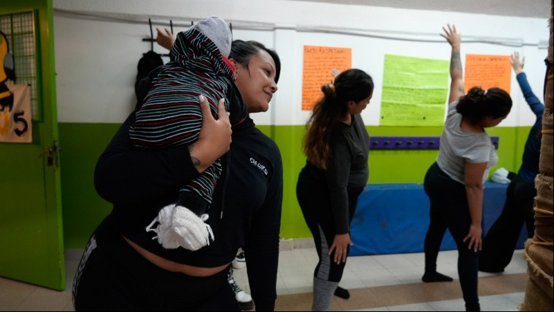 Una mujer realiza ejercicios de estiramiento con su beba de 6 meses.